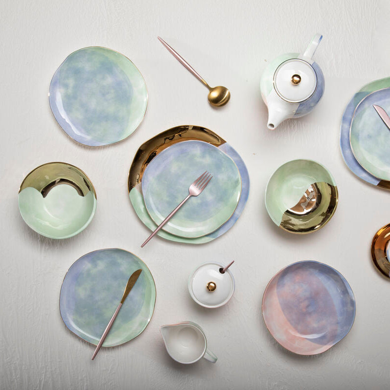 Collection of ceramic plates and tea sets on a light gray background