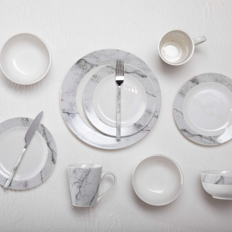 Set of marble-patterned ceramic dinnerware on a light gray background