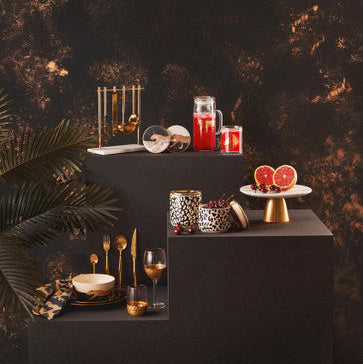 Decorative setup with candles, glasses, and fruit on a dark surface with a dark background