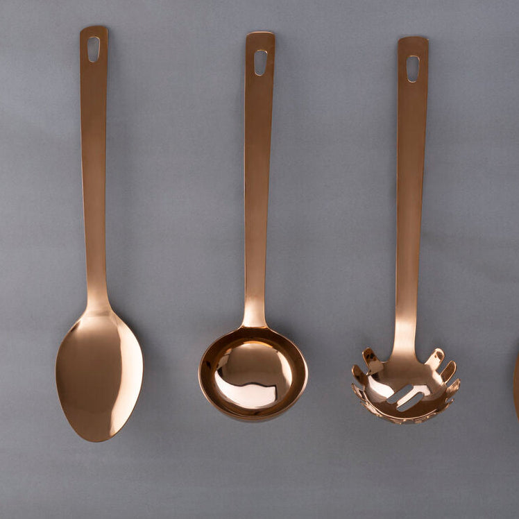 Set of four bronze-colored kitchen utensils on a gray background