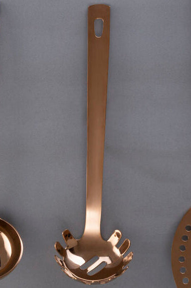 Set of four bronze-colored kitchen utensils on a gray background