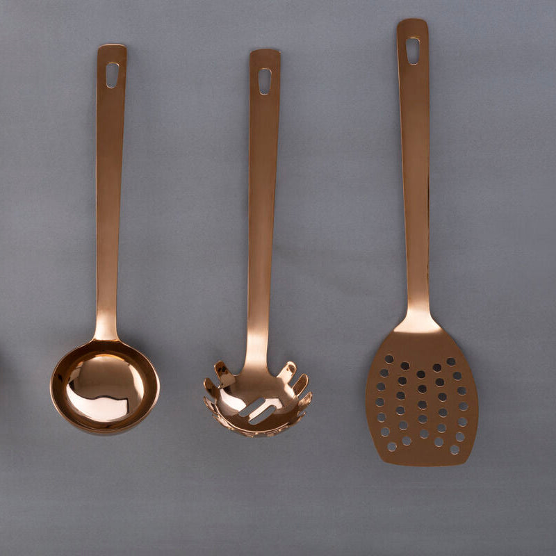 Set of four bronze-colored kitchen utensils on a gray background