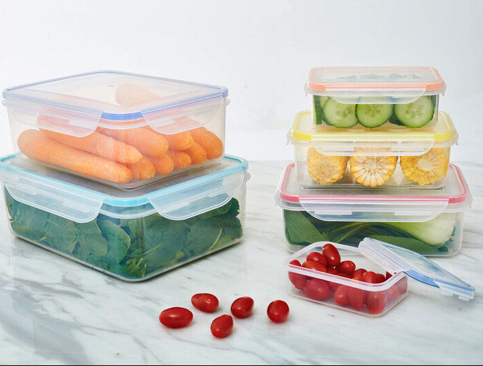 Set of food storage containers with vegetables on a marble surface
