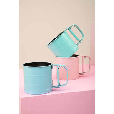 Three colorful mugs stacked on a pink surface with a light pink background