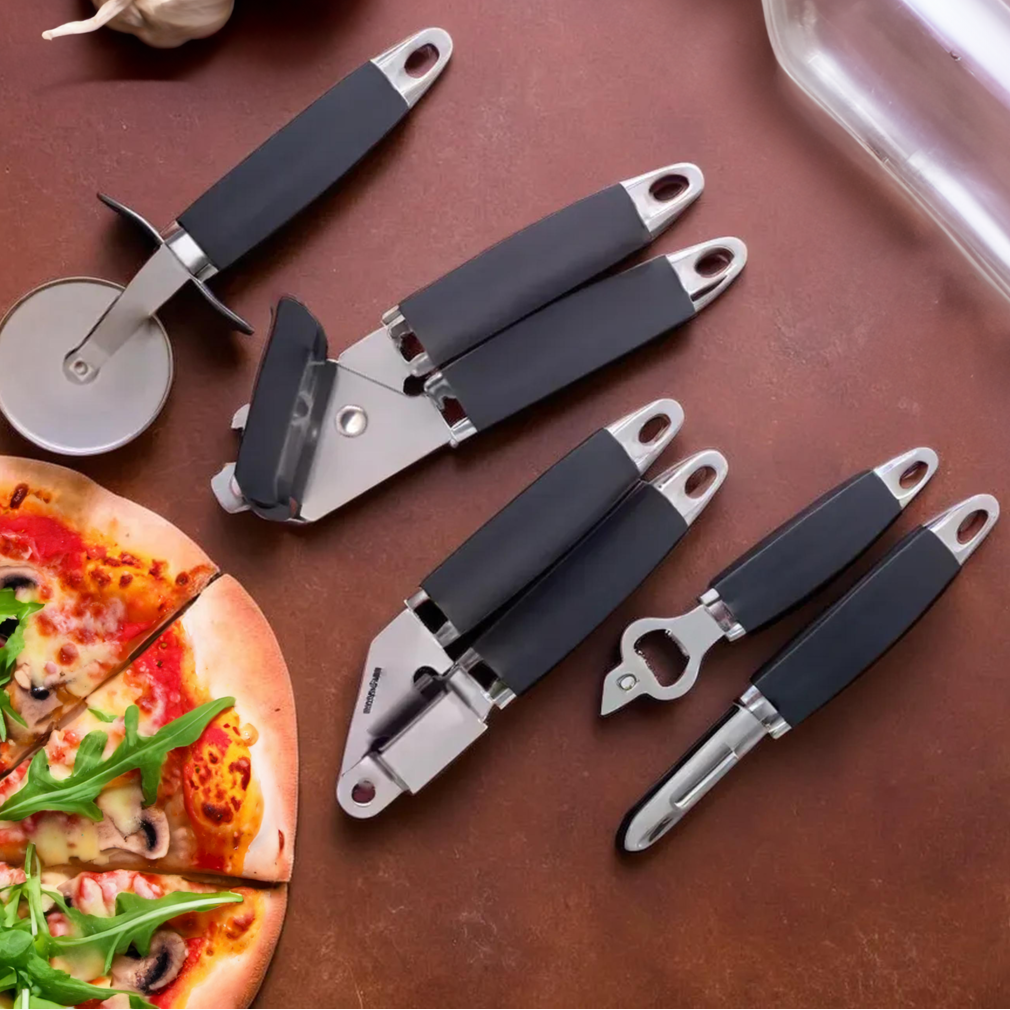 Set of kitchen tools with silicone handles on a brown surface with garlic and pizza.