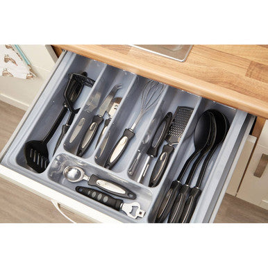 Set of kitchen utensils in a drawer organizer on a wooden countertop.