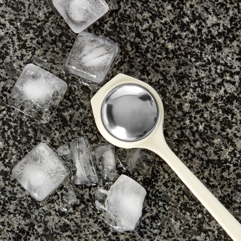 Spoon surrounded by ice cubes on a dark surface