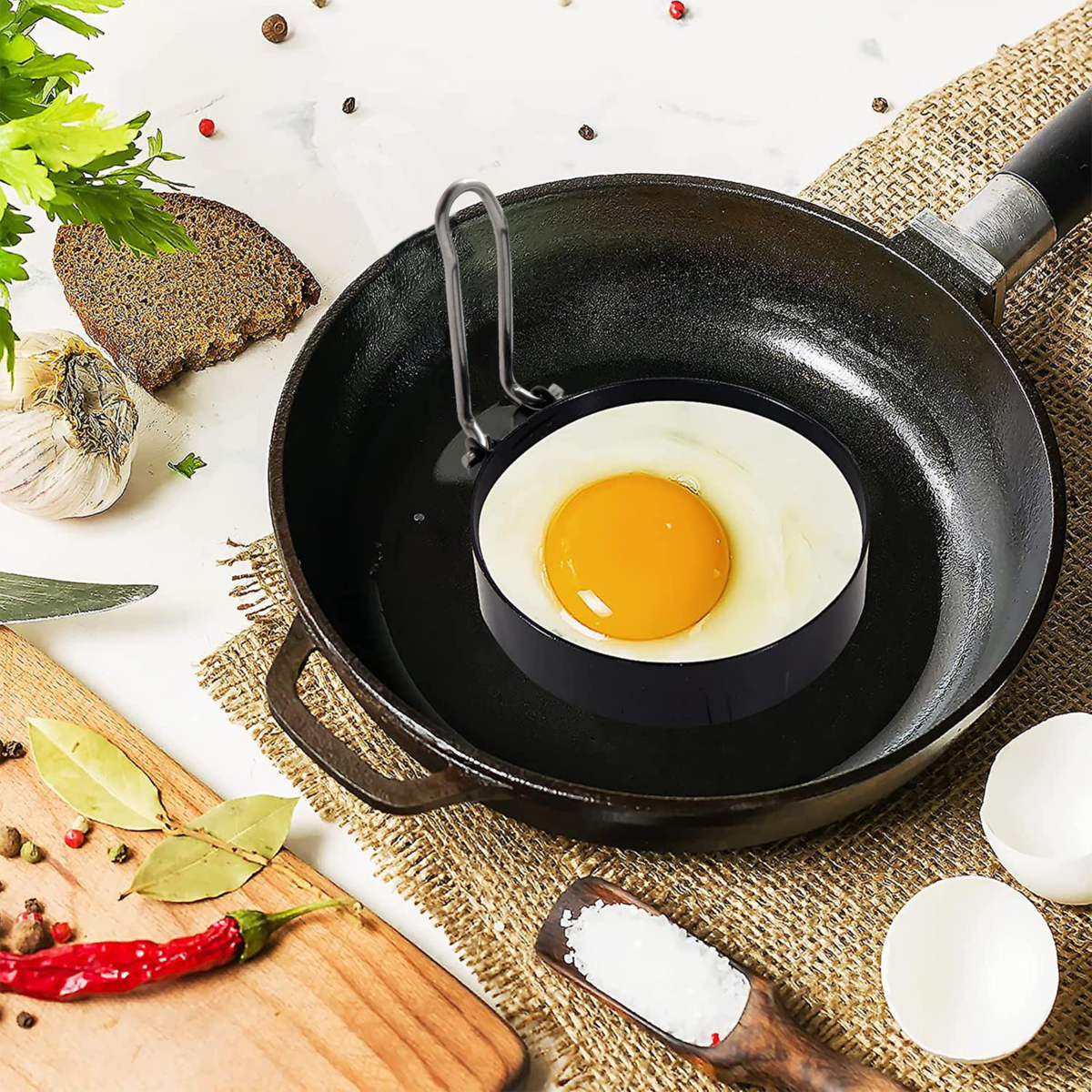 Fried egg in a black frying pan with a ring on a kitchen counter.