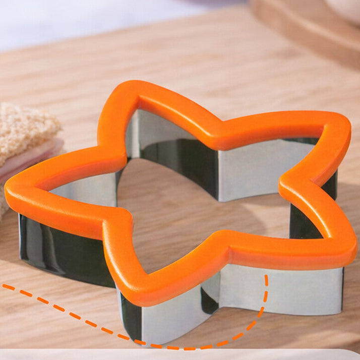 Star-shaped cookie cutter on a wooden board with sandwiches, surrounded by food items.