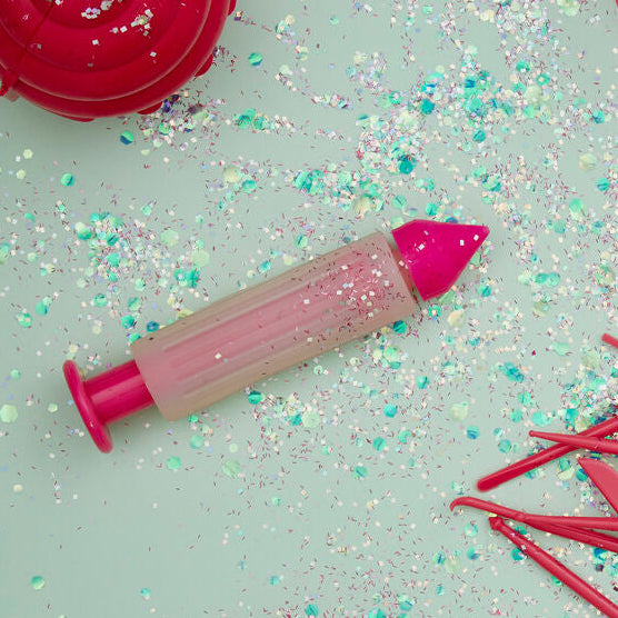 Pink baking tools and utensils on a light green surface with sprinkles.