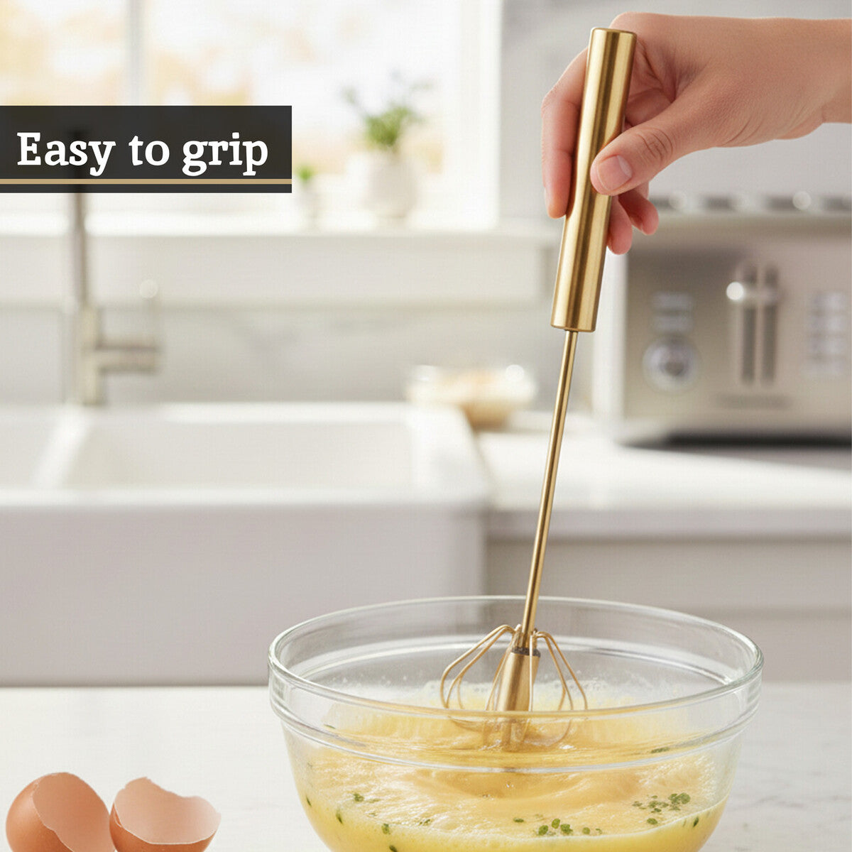 Gold whisk being used to mix ingredients in a bowl with a kitchen background.