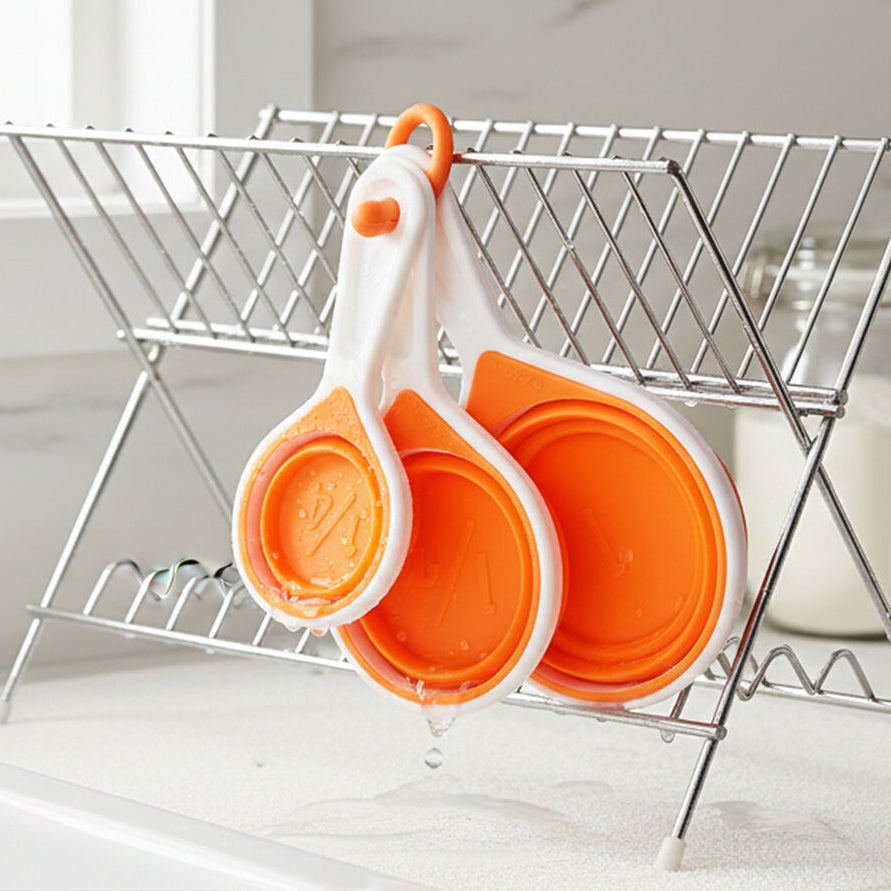 Orange measuring cups on a metal dish drying rack with &