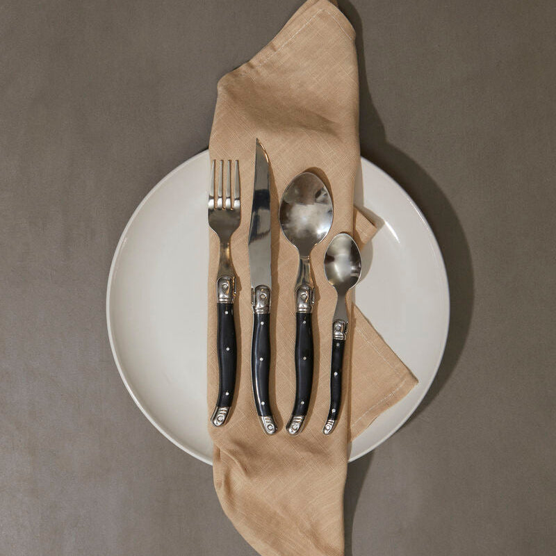 Set of cutlery on a white plate with a beige napkin against a gray background