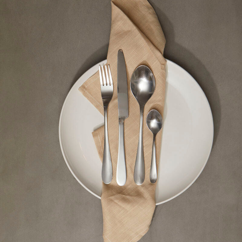 Silverware set on a white plate with a brown napkin against a gray background