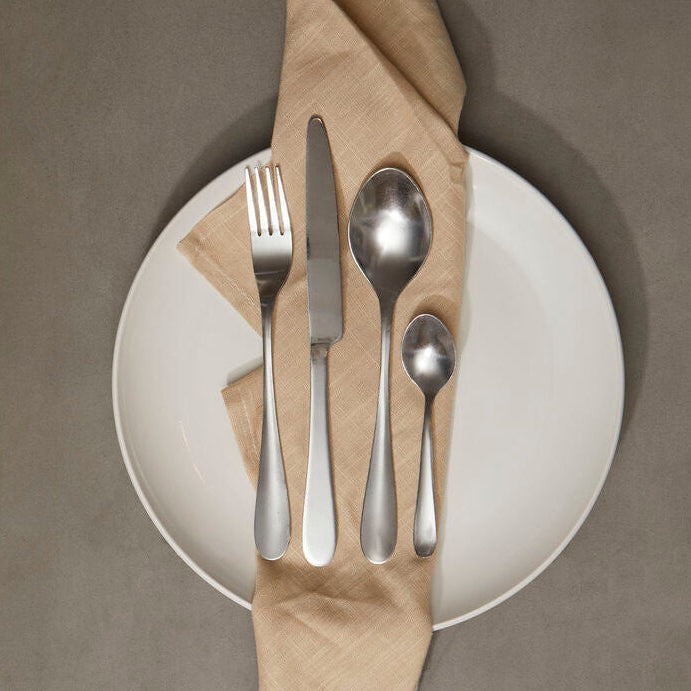 Silverware set on a white plate with a brown napkin against a gray background