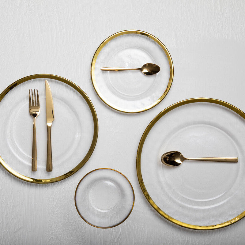 Set of gold-rimmed plates with cutlery on a white background
