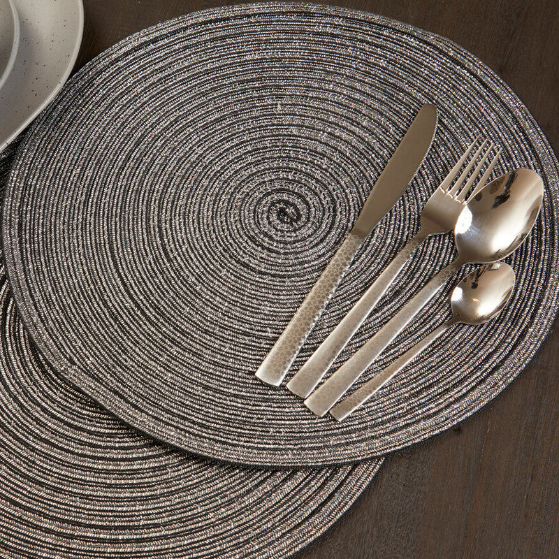 Round woven placemats with cutlery on a wooden table