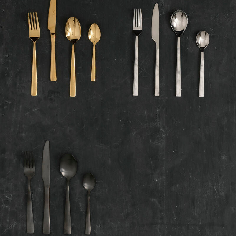 Set of gold and silver flatware on a dark surface