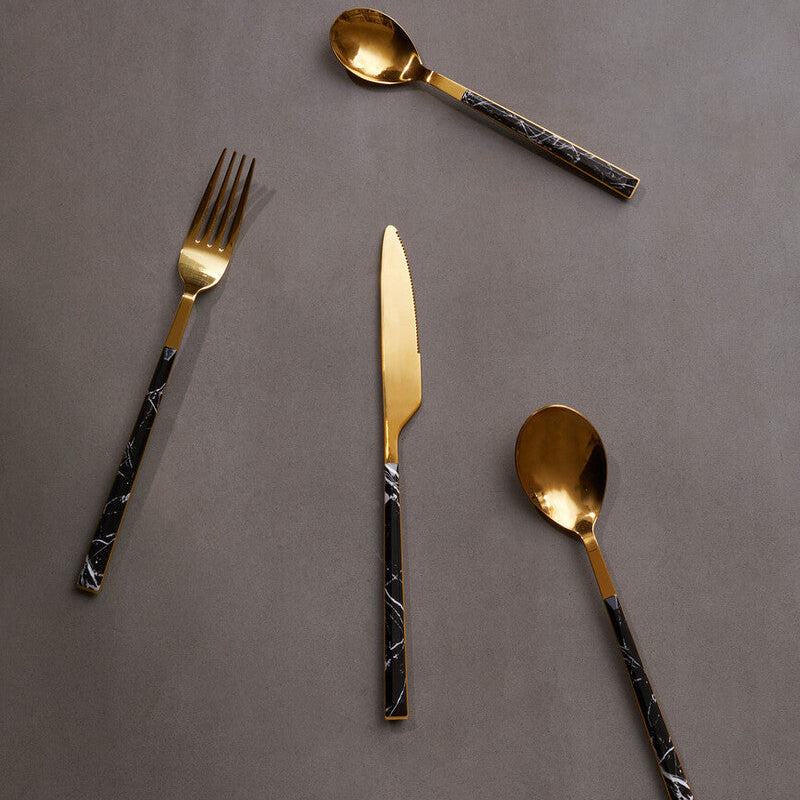 Set of gold and black patterned cutlery on a gray background