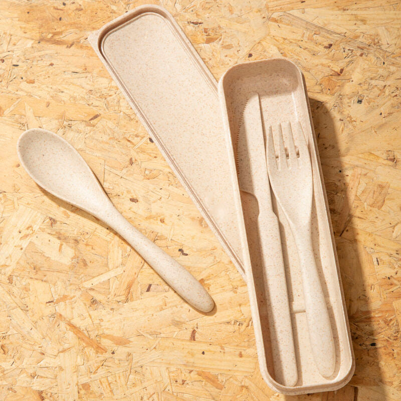 Set of wooden cutlery including a spoon, fork, and knife in a beige case on a wooden surface.