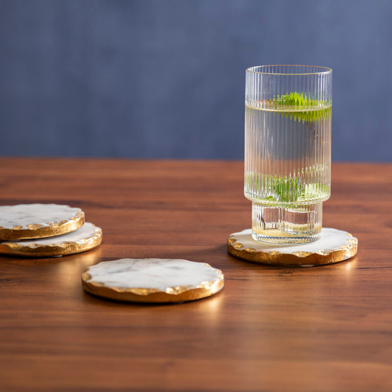 Glass with a drink on a wooden coaster on a wooden table with a blue background