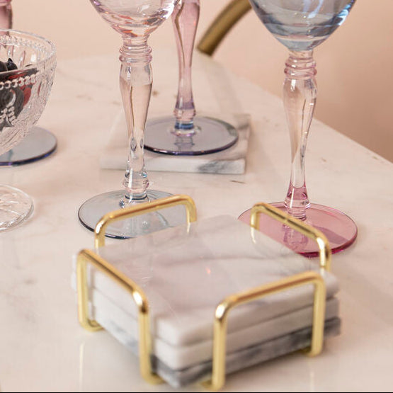Set of colorful glassware on a marble surface with a gold holder.