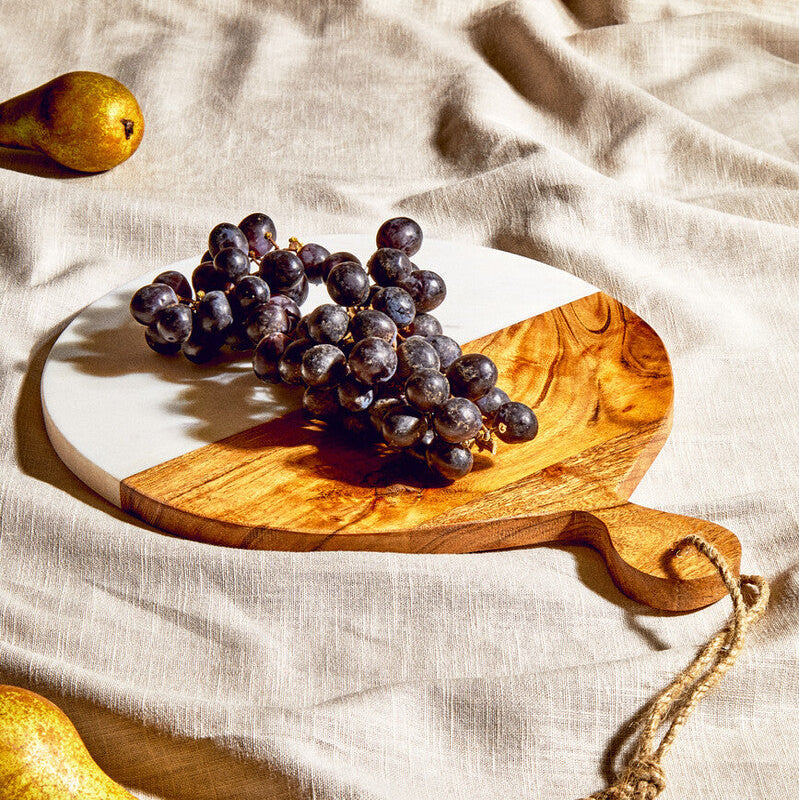 Bunch of grapes on a wooden cutting board with pears on a beige cloth background
