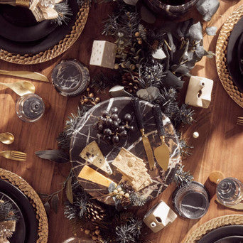 Decorative table setting with wine, plates, and centerpieces on a wooden table.