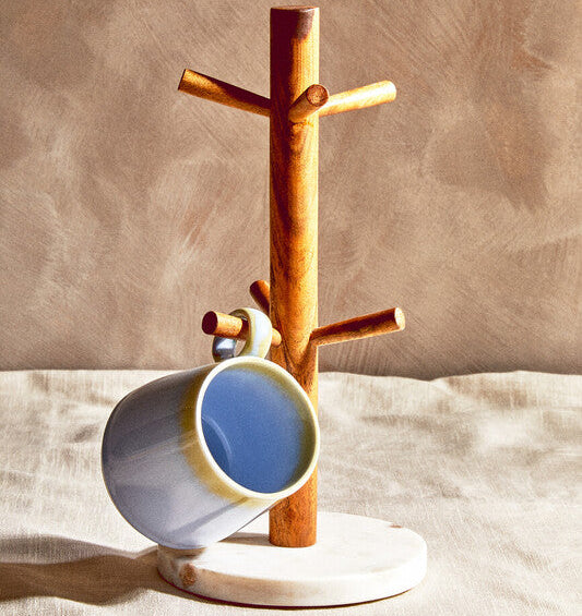 Wooden cup tree with a ceramic mug on a beige background