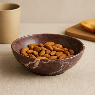 Marble-patterned bowl filled with almonds on a beige surface.