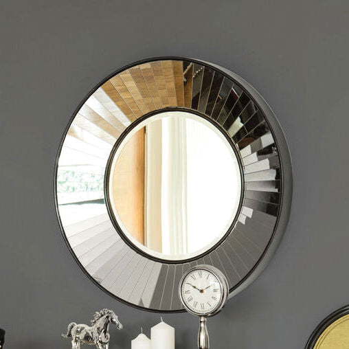 Two chairs and a round mirror in a room with a gray wall.