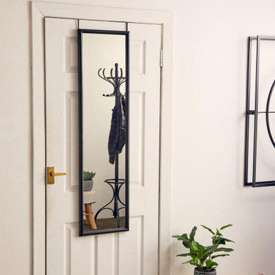 Full-length mirror with coat rack attached to a white door in a room with a plant and wooden bench.