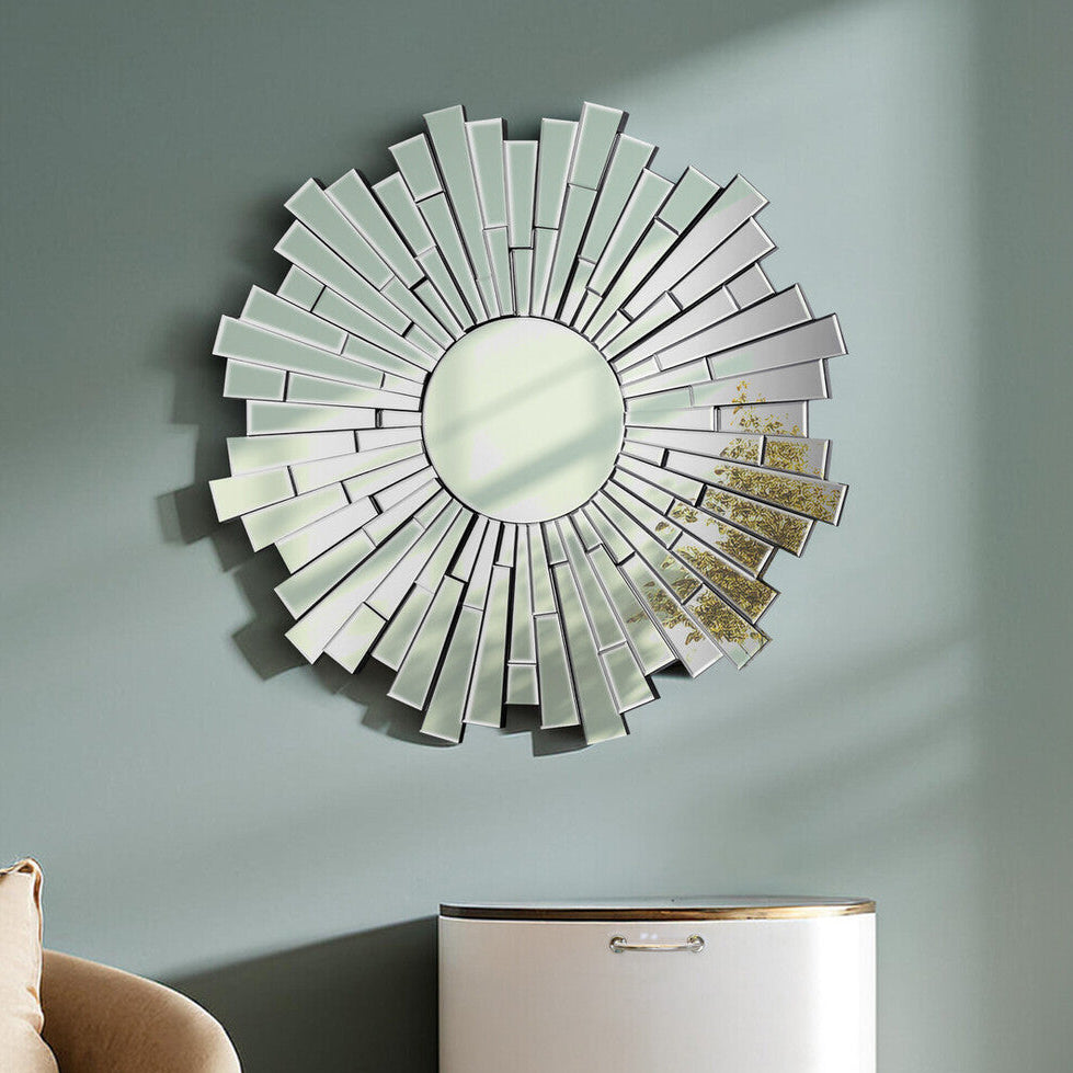 Decorative wall mirror with a sunburst design on a gray wall above a beige armchair and white cabinet.