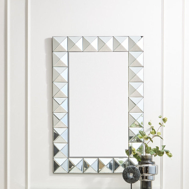 Decorative wall mirror with geometric frame on a white wall