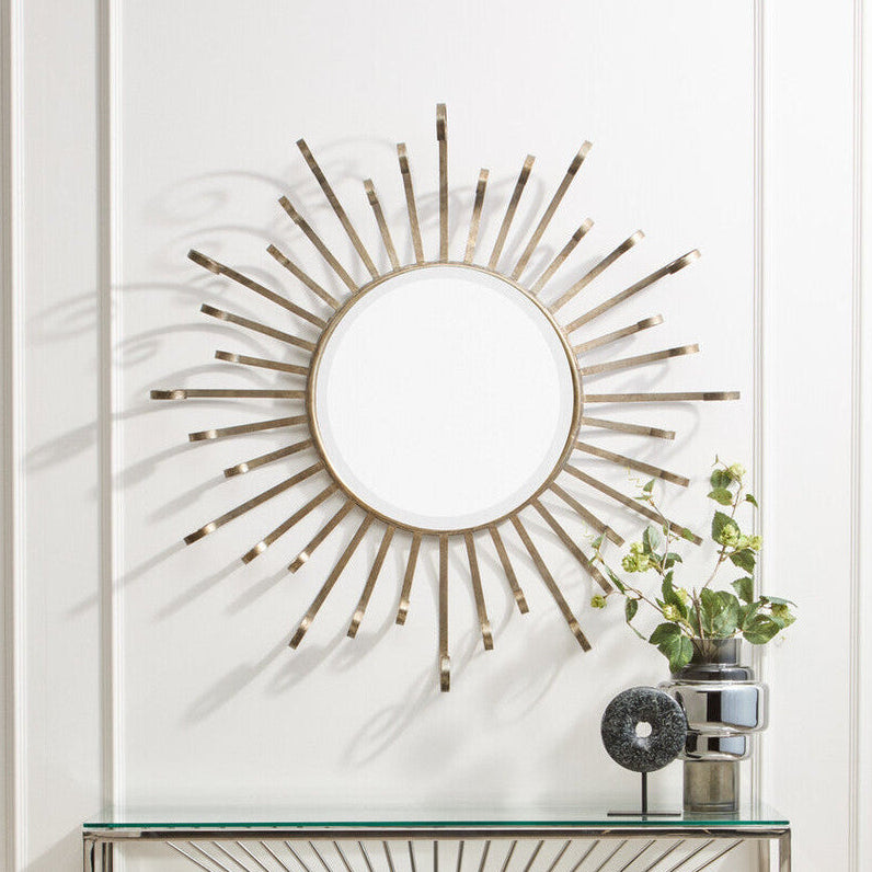 Decorative wall mirror with sunburst design on a white wall