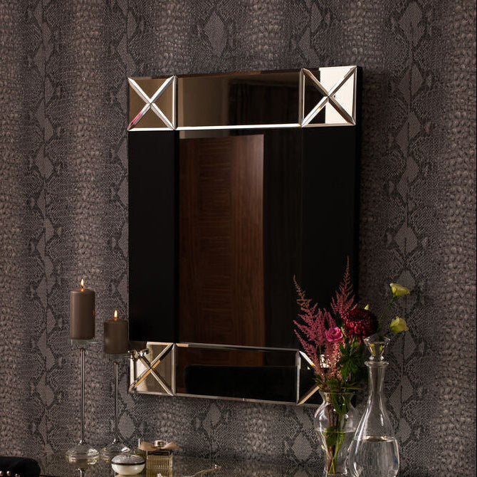 Decorative mirror on a wall with a dark, patterned wallpaper background.