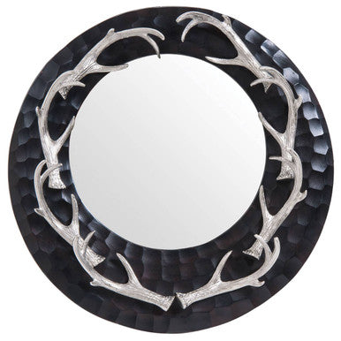 Round mirror with silver antler-like frame on a black background