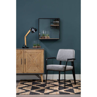 Gray chair in a room with a wooden cabinet, mirror, and decorative items.