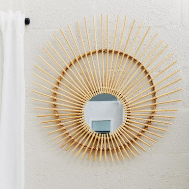 Round rattan mirror on a textured white wall