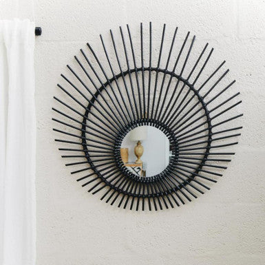 Decorative wall mirror with sunburst design on a white wall