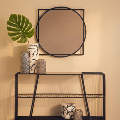 Black metal console table with decorative items against a beige wall