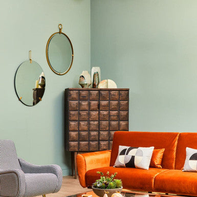 Modern living room with orange sofa, glass coffee table, and decorative elements.