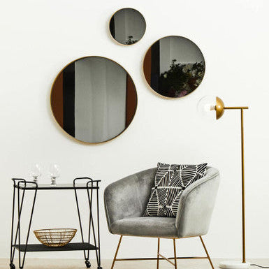 Modern interior with a gray armchair, round mirrors, and a floor lamp.