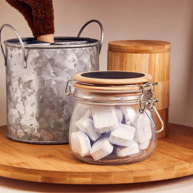 Decorative items including a metal bucket, wooden container, and glass jar with a wooden lid on a wooden surface.