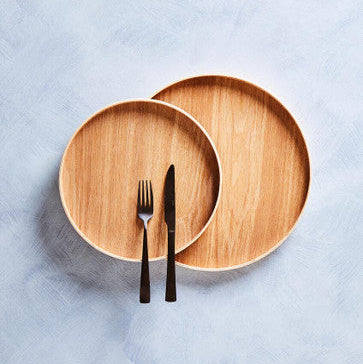 Two wooden plates with a fork and knife on a light blue textured surface