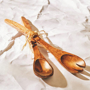 Three wooden measuring spoons tied together on a textured white surface