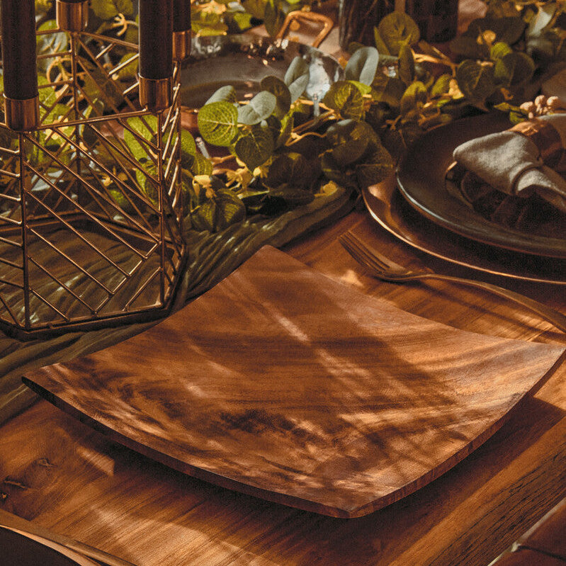 Wooden table setting with plates, napkins, and glasses on a wooden table.