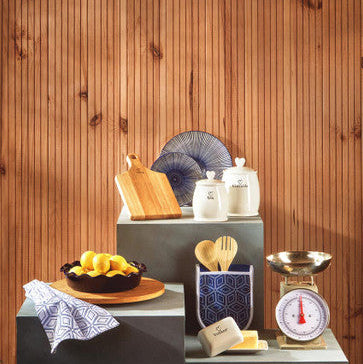 Kitchen counter with various items including a bowl of lemons, cutting board, and scale against a wooden wall.
