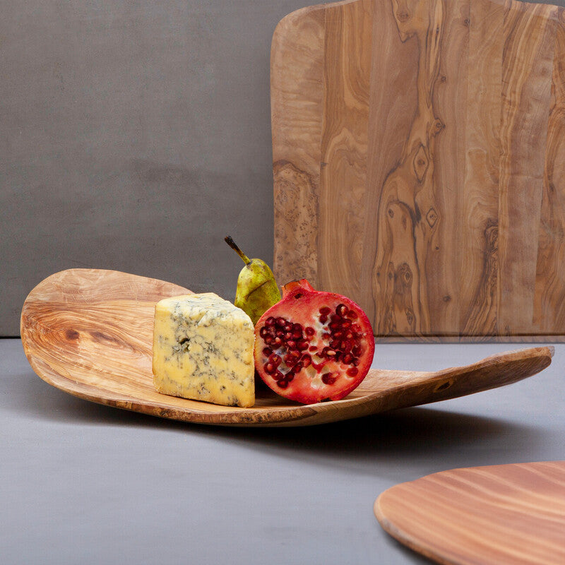 Wooden platter with cheese and pomegranate on a gray surface