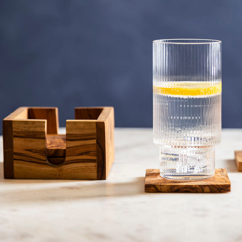 Clear glass with a wooden coaster on a light surface with a dark background
